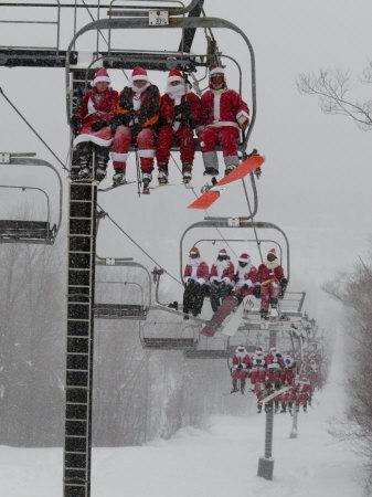 Skiers and Snowboarders Dressed as Santa Claus Ride up the Ski Lift - Photographic Print, 12x16